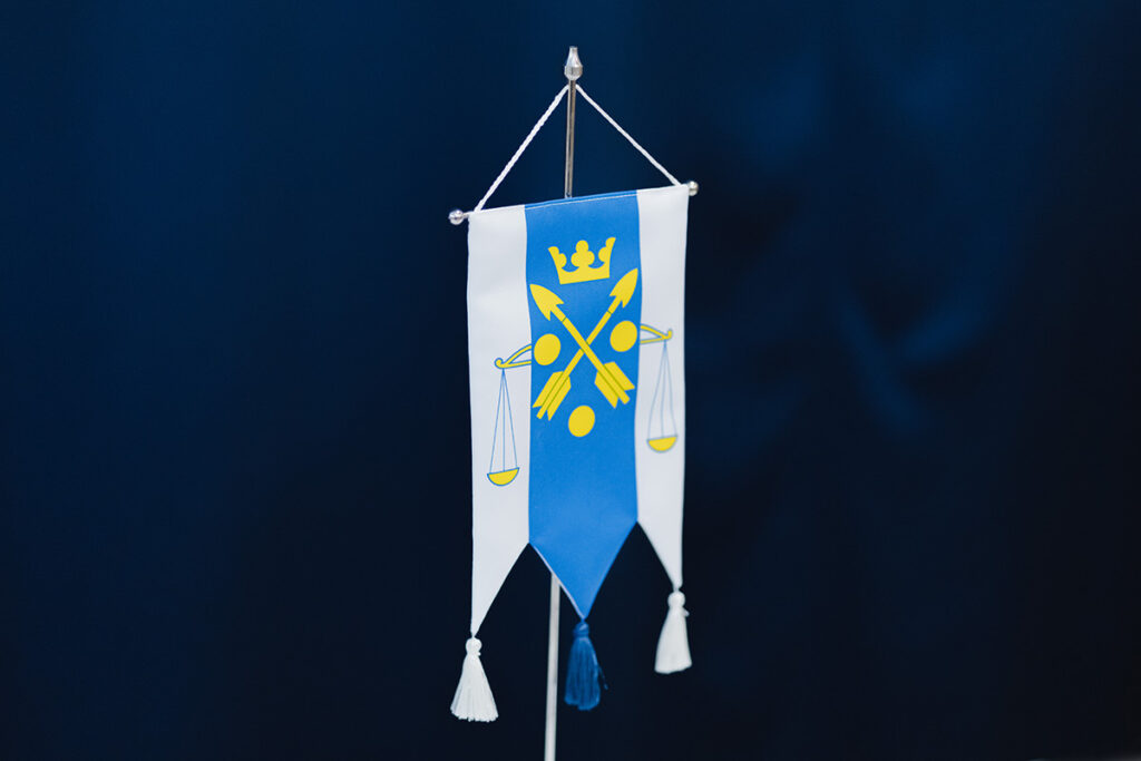 Verovirkailijain Liiton viiri: vaaka, kaksi nuolta ristissä, kolme ympyrää ja kruunu.