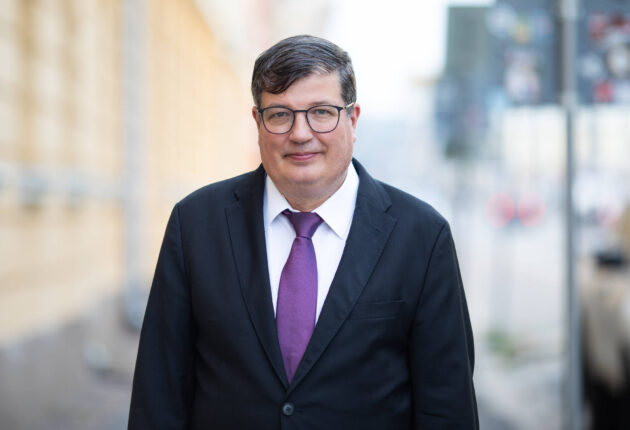 Työministeri Arto Satonen. Ministerin taustalla on katunäkymä.