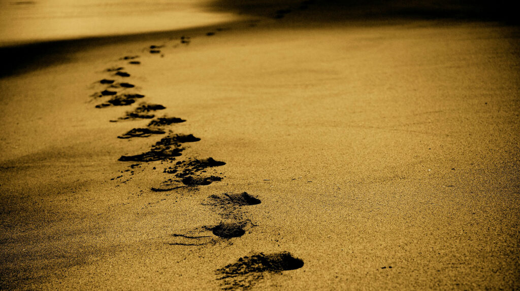 Jalanjäljet kulkevat hiekan poikki.