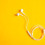 Korvanappikuulokkeet, johto ja liitin. Värikäs tausta. Kuva: Pixabay.