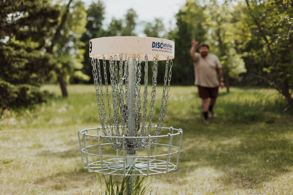 Henkilö heittää frisbeetä frisbeegolf-koriin. Kuva: Priscilla Du Preez/Unsplash.