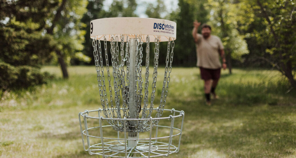 Henkilö heittää frisbeetä frisbeegolf-koriin. Kuva: Priscilla Du Preez/Unsplash.